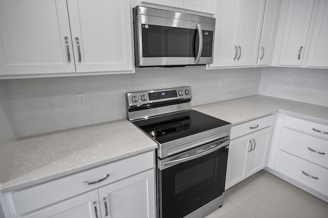 kitchen with white cabinetry, stainless steel appliances, and backsplash