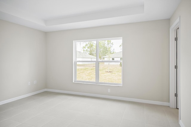 tiled spare room featuring a raised ceiling