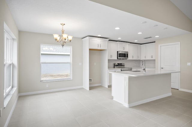 kitchen featuring sink, a center island with sink, hanging light fixtures, stainless steel appliances, and white cabinets