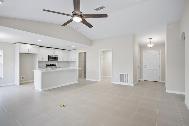 unfurnished living room with light tile patterned flooring, ceiling fan, sink, and vaulted ceiling