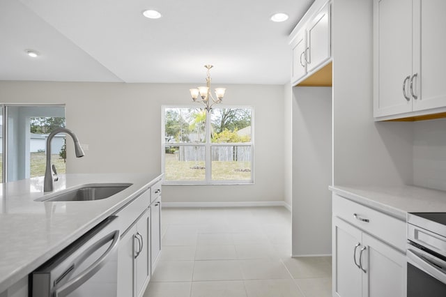 kitchen featuring dishwashing machine, sink, light tile patterned floors, white cabinetry, and decorative light fixtures