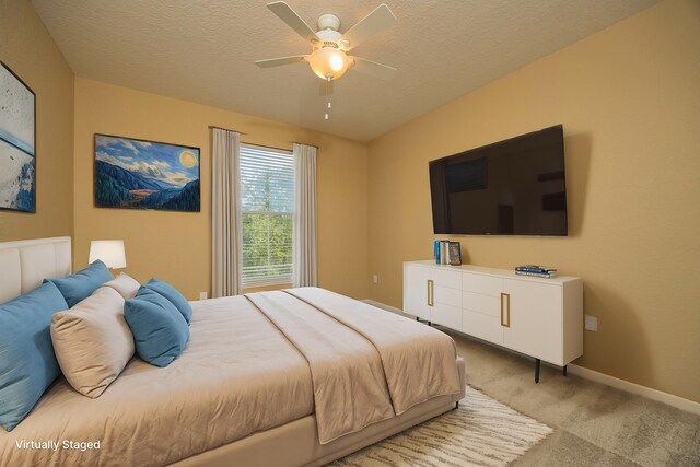 carpeted bedroom featuring ceiling fan and a textured ceiling