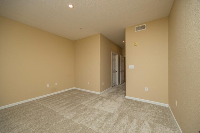 carpeted spare room with a textured ceiling