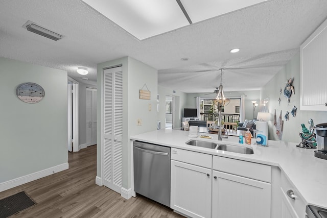 kitchen with sink, dishwasher, white cabinetry, a textured ceiling, and light wood-type flooring