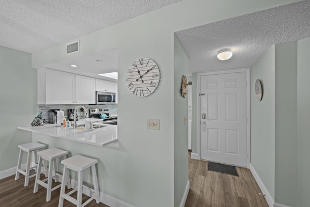 kitchen with sink, white cabinetry, tasteful backsplash, appliances with stainless steel finishes, and a kitchen breakfast bar