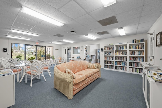 living room featuring dark colored carpet and a paneled ceiling