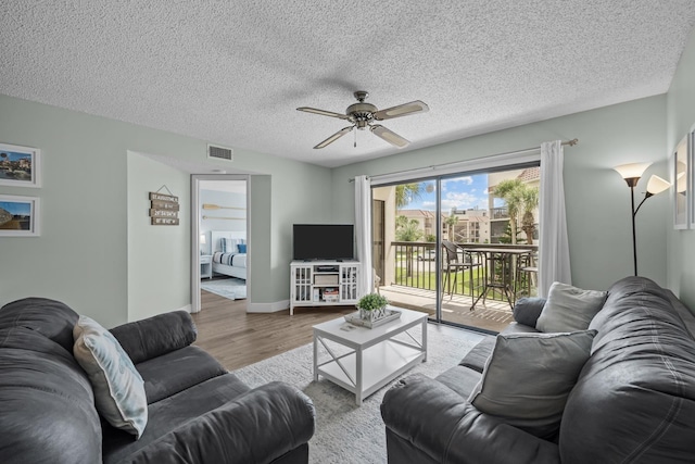 living room with ceiling fan, a textured ceiling, and light hardwood / wood-style flooring