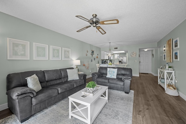 living room with hardwood / wood-style floors, ceiling fan with notable chandelier, and a textured ceiling