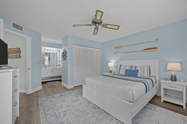 bedroom with ensuite bathroom, light hardwood / wood-style flooring, a textured ceiling, a closet, and ceiling fan