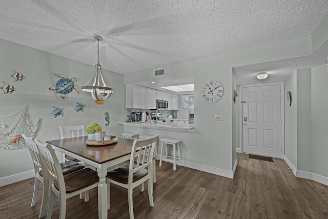 dining room with sink, dark wood-type flooring, and a textured ceiling