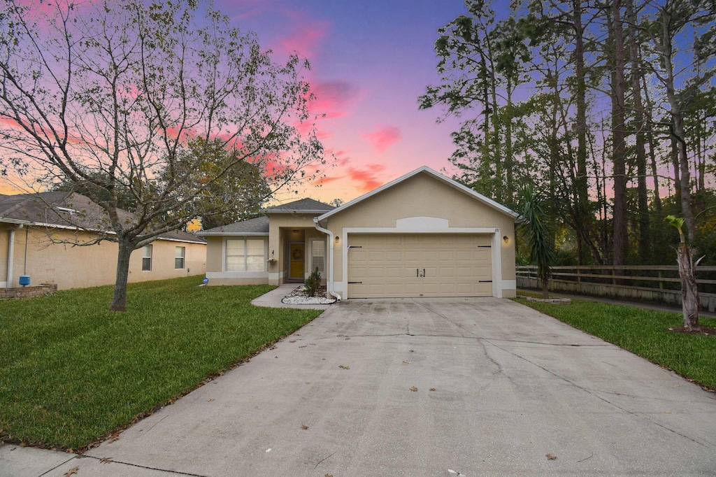 ranch-style house with a garage and a lawn