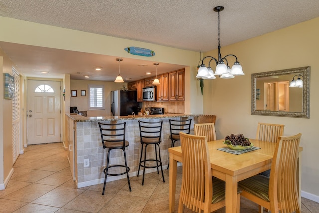 dining area with a chandelier, light tile patterned floors, and a textured ceiling