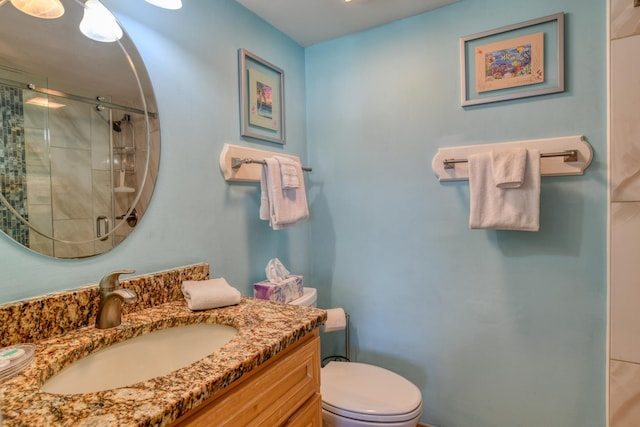 bathroom featuring vanity, toilet, and a shower with door