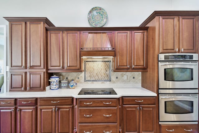 kitchen with black electric cooktop, custom range hood, double oven, and tasteful backsplash