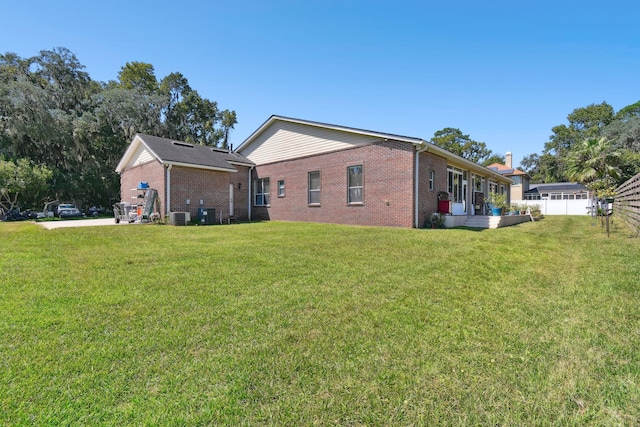 rear view of property with a lawn and central AC unit