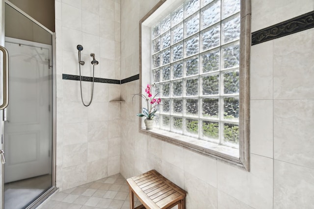 bathroom with tiled shower, tile patterned flooring, and tile walls