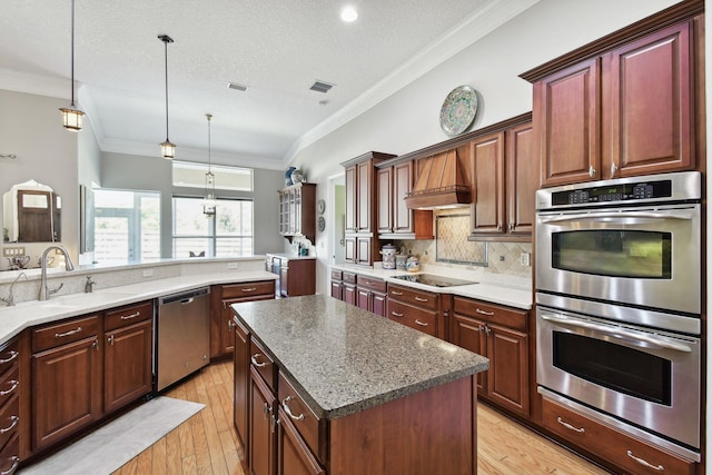 kitchen with crown molding, sink, hanging light fixtures, light hardwood / wood-style flooring, and stainless steel appliances