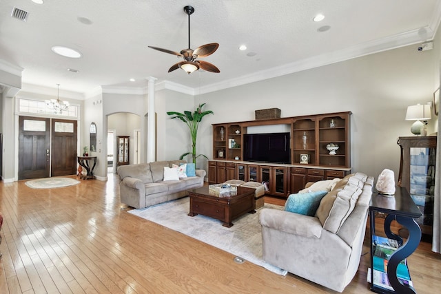 living room featuring a textured ceiling, ceiling fan with notable chandelier, light wood-type flooring, and ornamental molding