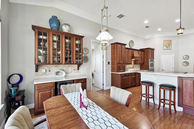 dining area with wine cooler, hardwood / wood-style floors, a textured ceiling, lofted ceiling, and ornamental molding