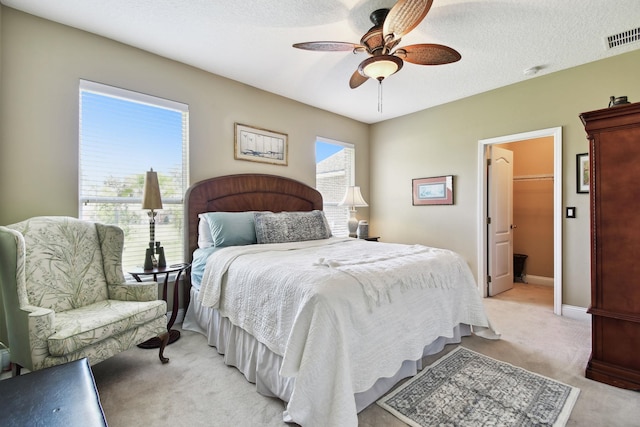 bedroom featuring ceiling fan, a walk in closet, light carpet, and a closet