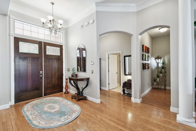 foyer entrance with light wood-type flooring, an inviting chandelier, and ornamental molding