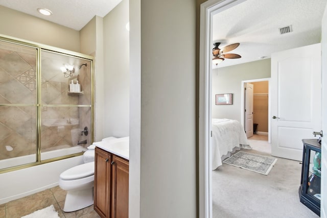 full bathroom featuring tile patterned flooring, enclosed tub / shower combo, a textured ceiling, toilet, and vanity