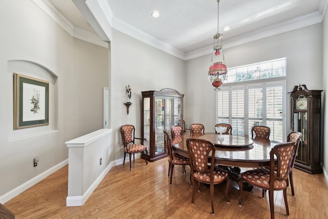 dining area featuring crown molding, light hardwood / wood-style flooring, and a textured ceiling