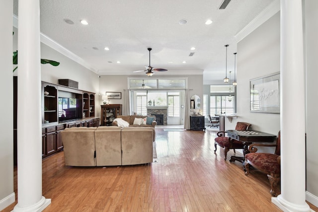 living room with crown molding, light hardwood / wood-style flooring, ceiling fan, ornate columns, and a textured ceiling