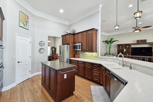 kitchen featuring a textured ceiling, sink, light wood-type flooring, and stainless steel appliances