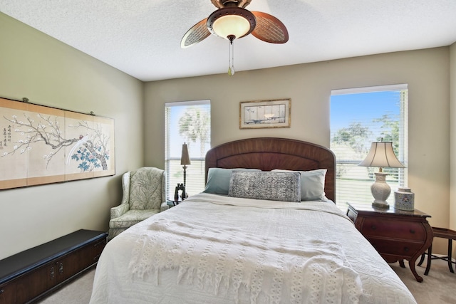 bedroom featuring light carpet, ceiling fan, and a textured ceiling