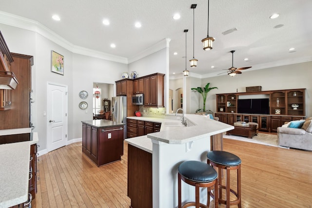 kitchen featuring a kitchen breakfast bar, sink, light hardwood / wood-style flooring, appliances with stainless steel finishes, and kitchen peninsula