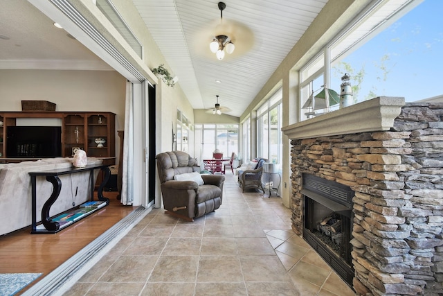 interior space with a stone fireplace, ceiling fan, and vaulted ceiling