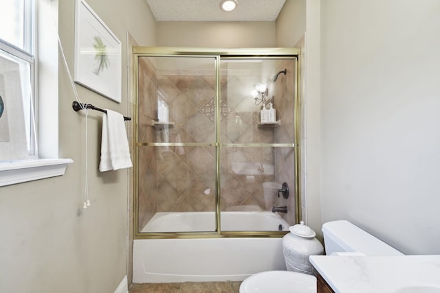 full bathroom with shower / bath combination with glass door, vanity, a textured ceiling, and toilet