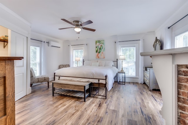 bedroom with a wall mounted air conditioner, ceiling fan, ornamental molding, and light hardwood / wood-style flooring