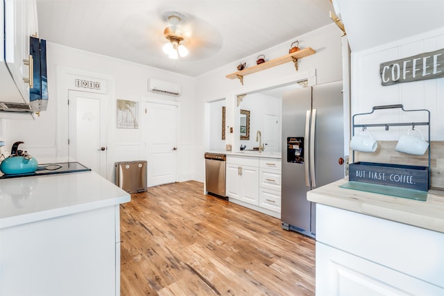 kitchen with stainless steel appliances, sink, light hardwood / wood-style flooring, an AC wall unit, and white cabinets