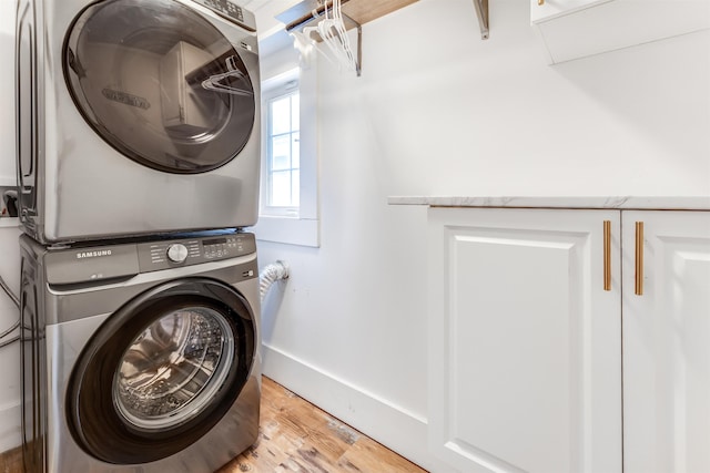 laundry area with stacked washing maching and dryer and light hardwood / wood-style floors