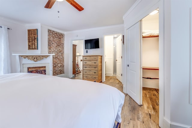 bedroom featuring ensuite bathroom, light hardwood / wood-style flooring, ceiling fan, ornamental molding, and a closet