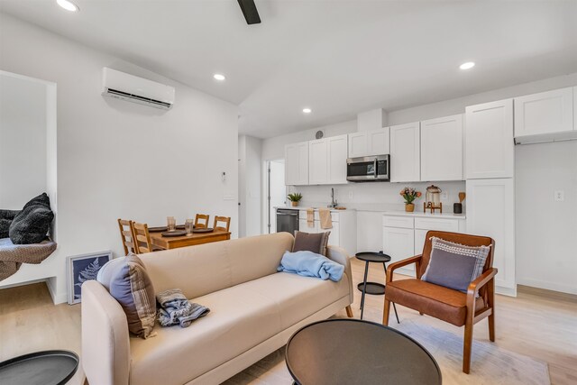 living room featuring light hardwood / wood-style floors, an AC wall unit, and sink