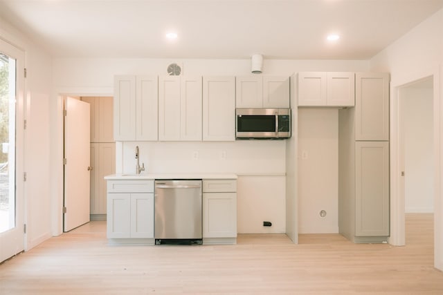 kitchen with light wood-type flooring, sink, and appliances with stainless steel finishes