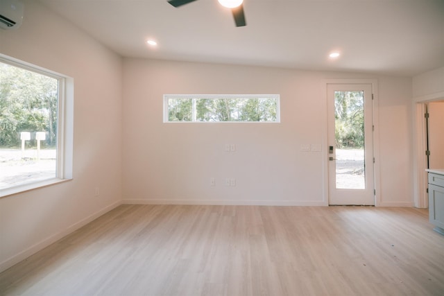 empty room with ceiling fan, light hardwood / wood-style flooring, and a wall mounted air conditioner