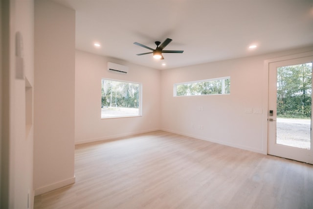 spare room with light wood-type flooring, an AC wall unit, and ceiling fan