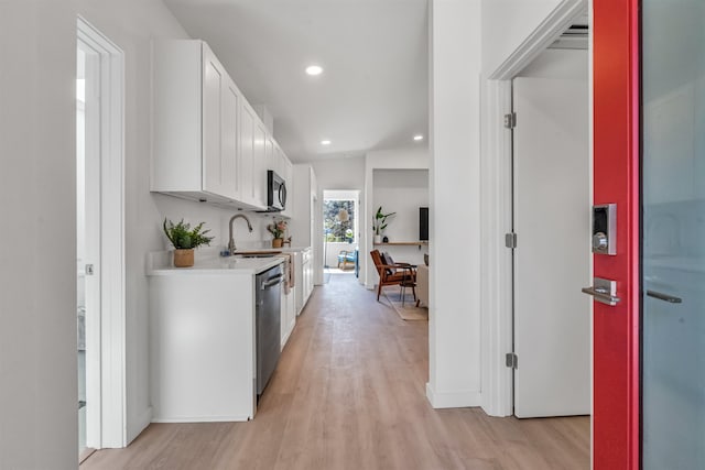 kitchen featuring white cabinetry, sink, appliances with stainless steel finishes, and light hardwood / wood-style flooring