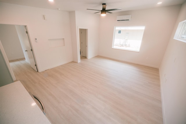 unfurnished room featuring a wall mounted air conditioner, light hardwood / wood-style floors, a wealth of natural light, and ceiling fan