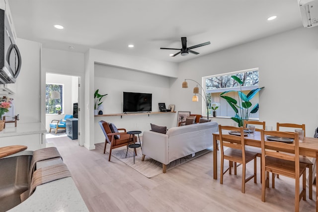 living room featuring ceiling fan, light hardwood / wood-style floors, and a wall mounted air conditioner