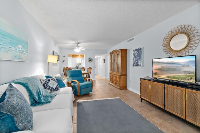 living room with a textured ceiling, a ceiling fan, and tile patterned flooring
