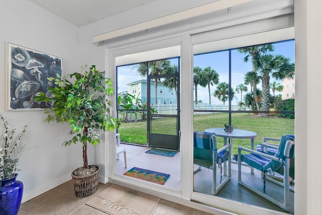 doorway with plenty of natural light, baseboards, a textured ceiling, and tile patterned floors