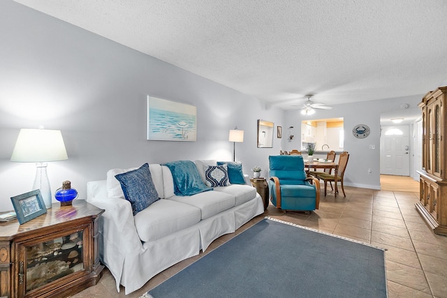 living room featuring a textured ceiling, ceiling fan, and light tile patterned flooring