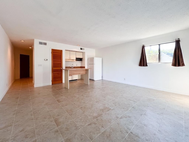 unfurnished living room featuring light tile patterned floors and a textured ceiling