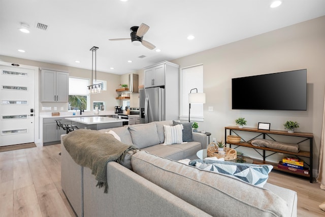 living room featuring ceiling fan, sink, and light hardwood / wood-style floors