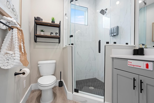 bathroom featuring vanity, hardwood / wood-style flooring, a shower with door, and toilet